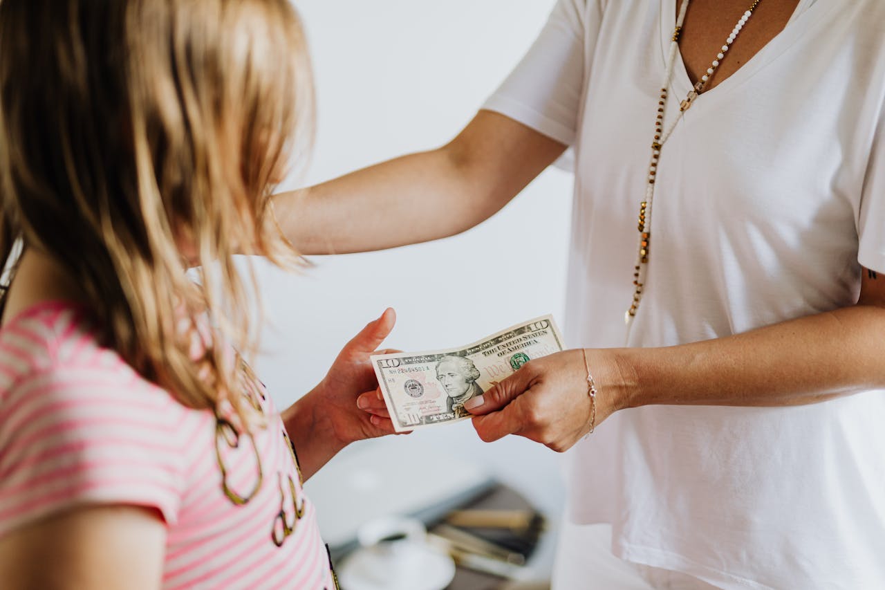 why-choose-us-02 A woman handing money to a young girl, symbolizing family financial education and transactions.